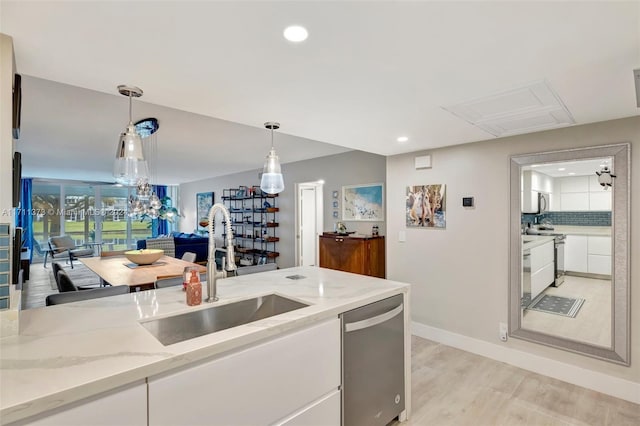 kitchen with light wood-type flooring, stainless steel dishwasher, sink, pendant lighting, and white cabinetry