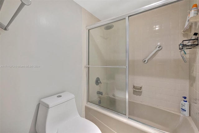 bathroom with combined bath / shower with glass door and toilet