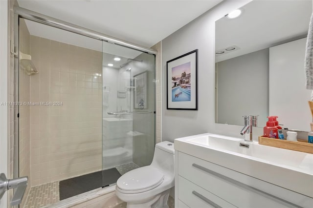 bathroom featuring a shower with door, vanity, and toilet