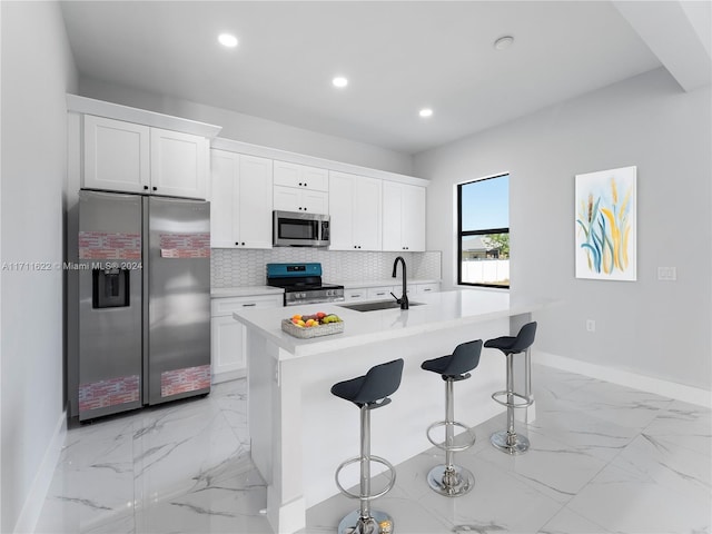 kitchen featuring a breakfast bar, a center island with sink, white cabinets, sink, and appliances with stainless steel finishes