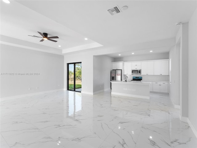 unfurnished living room featuring ceiling fan, a raised ceiling, and sink