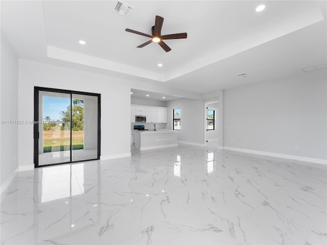 unfurnished living room with a raised ceiling and ceiling fan