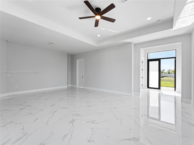 unfurnished room with a raised ceiling and ceiling fan