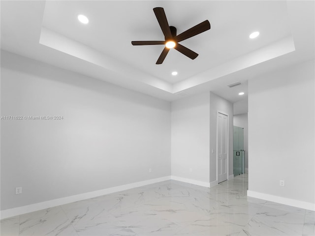 empty room featuring a raised ceiling and ceiling fan