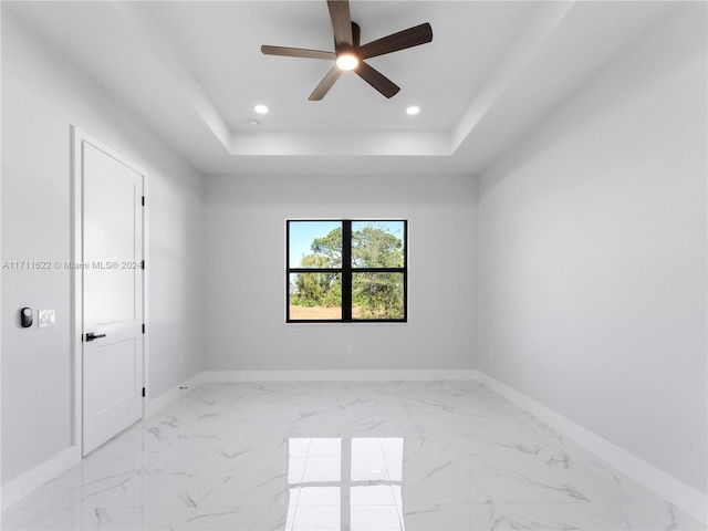 spare room with a raised ceiling and ceiling fan