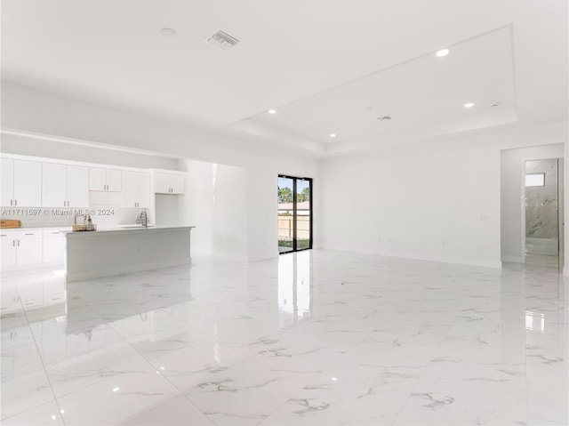 empty room with a raised ceiling and sink