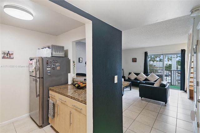 kitchen featuring stainless steel fridge, light brown cabinets, light tile patterned floors, and a textured ceiling