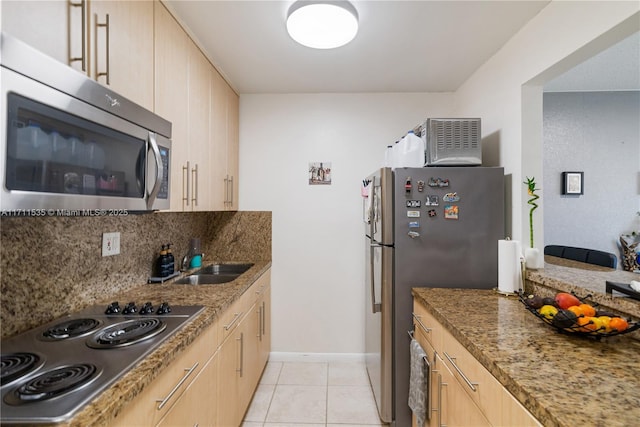 kitchen with stone counters, light brown cabinetry, light tile patterned floors, and stainless steel appliances