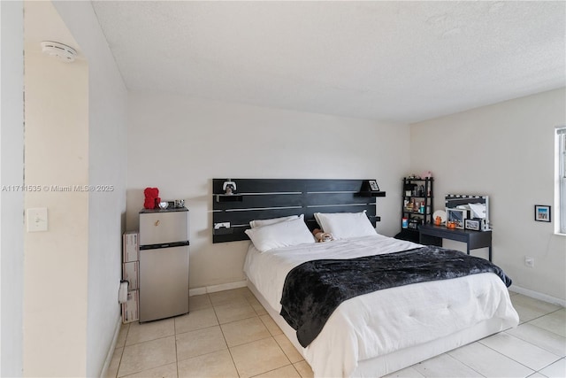 bedroom featuring stainless steel fridge, a textured ceiling, and light tile patterned floors