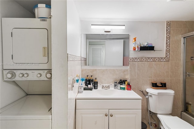 bathroom featuring vanity, stacked washing maching and dryer, tile walls, and toilet