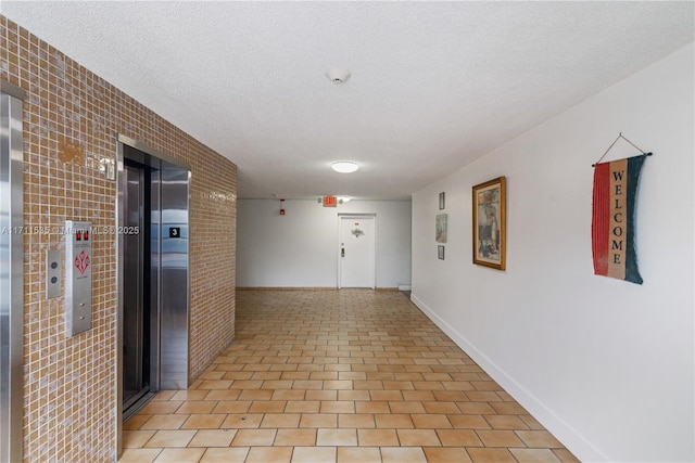 corridor featuring a textured ceiling and elevator