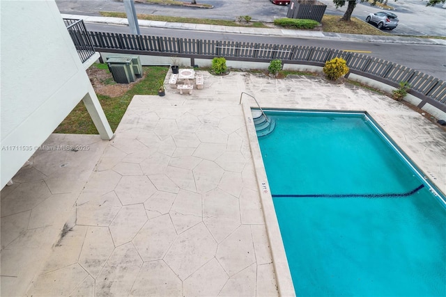 view of swimming pool featuring central AC unit and a patio