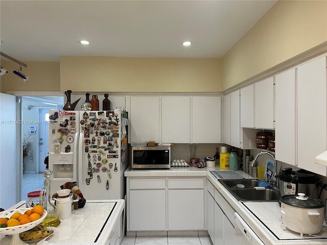 kitchen with tile countertops, white refrigerator with ice dispenser, and sink