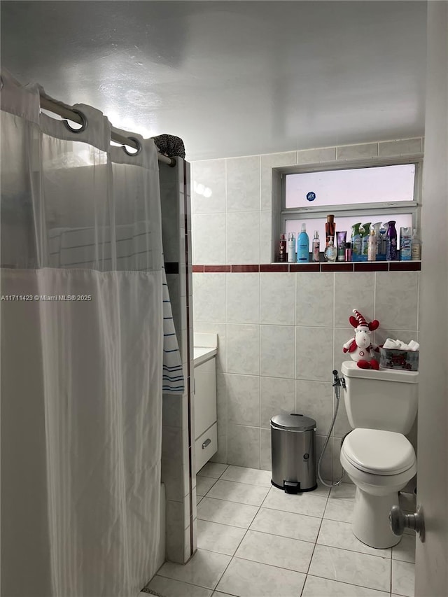 bathroom with toilet, vanity, tile walls, tile patterned floors, and washer / clothes dryer