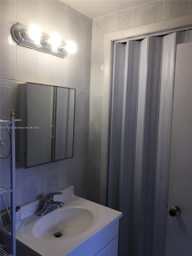 bathroom with tile walls, vanity, and tasteful backsplash