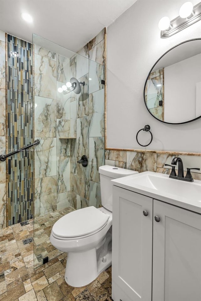 bathroom featuring toilet, vanity, tile walls, and tiled shower