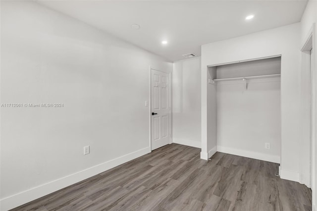 unfurnished bedroom featuring dark hardwood / wood-style floors and a closet