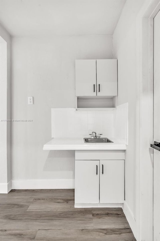 bar featuring white cabinetry, sink, and light hardwood / wood-style flooring