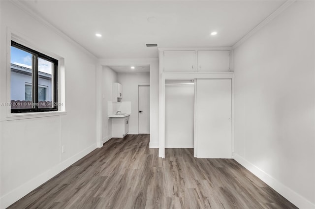 interior space featuring connected bathroom, ornamental molding, and light wood-type flooring