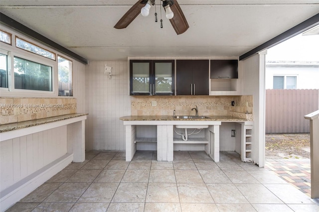 kitchen featuring dark brown cabinets, light tile patterned floors, a wealth of natural light, and wooden walls