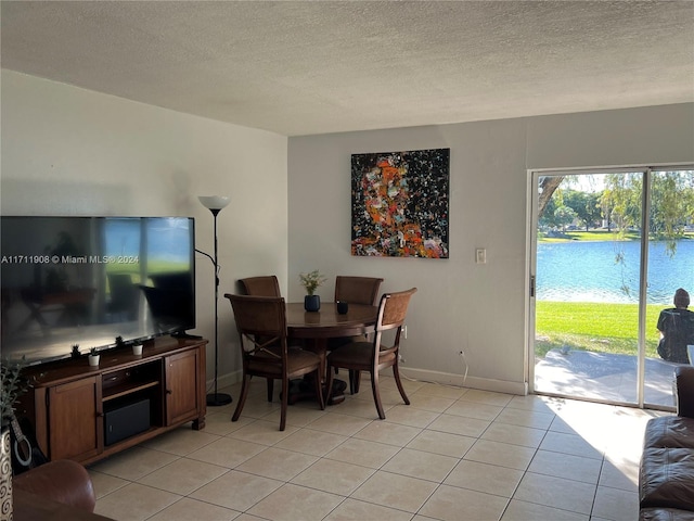 dining room featuring a water view, light tile patterned flooring, and a textured ceiling