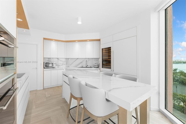 kitchen with white cabinets, appliances with stainless steel finishes, a center island, and decorative backsplash