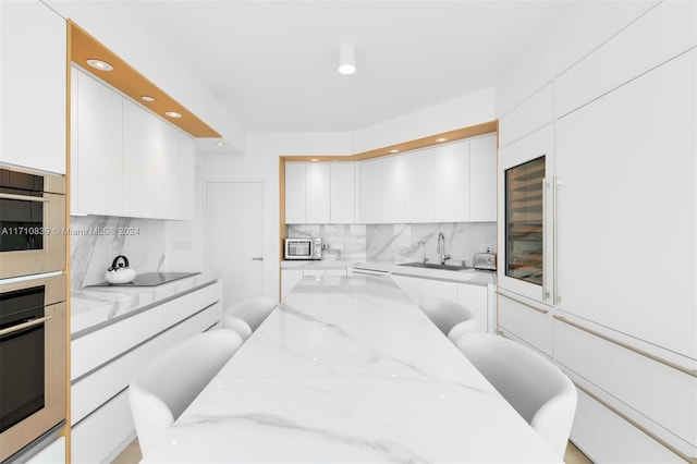 kitchen featuring light stone countertops, sink, black electric cooktop, decorative backsplash, and white cabinets