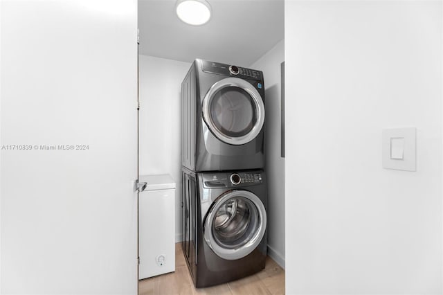 washroom with stacked washer and dryer and light hardwood / wood-style flooring