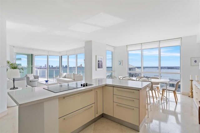 kitchen featuring a kitchen island, a water view, black electric cooktop, and cream cabinets