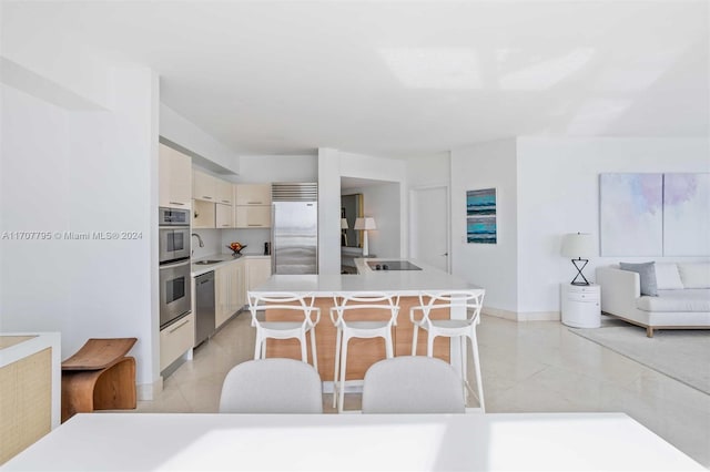 kitchen featuring light tile patterned flooring, sink, a kitchen island, a kitchen bar, and stainless steel appliances