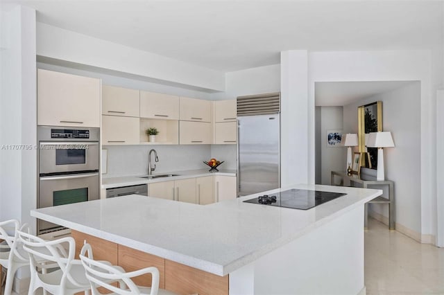 kitchen featuring cream cabinets, a kitchen breakfast bar, sink, a kitchen island, and stainless steel appliances