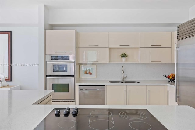 kitchen featuring cream cabinetry, backsplash, sink, and appliances with stainless steel finishes