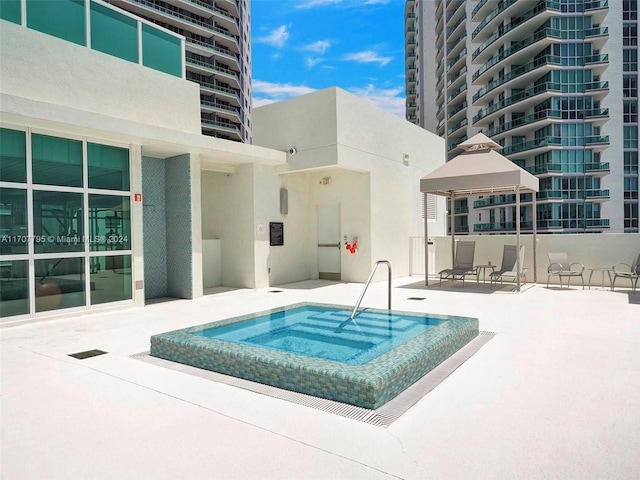 view of pool featuring a jacuzzi and a patio