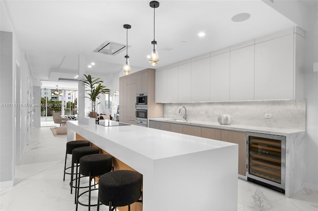 kitchen with hanging light fixtures, a center island with sink, beverage cooler, and sink