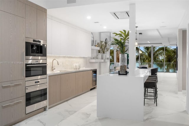 kitchen featuring a kitchen bar, light brown cabinetry, backsplash, sink, and a center island