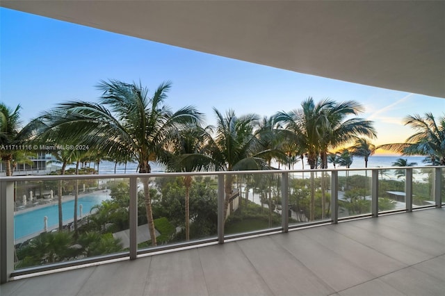 balcony at dusk featuring a water view