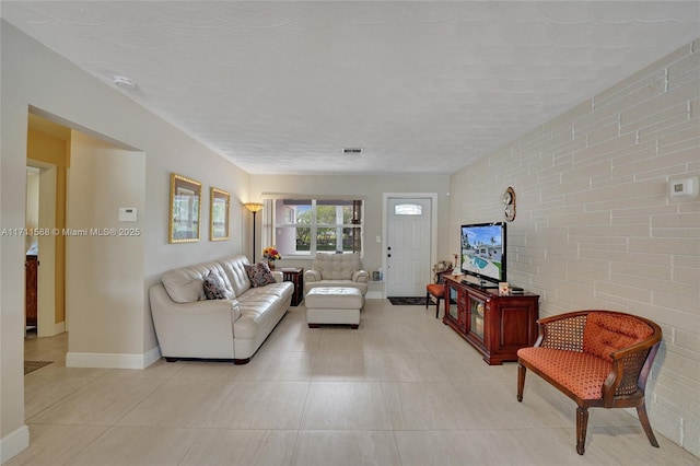 1407 Harding St, Hollywood, FL 33020 - living room featuring light tile patterned floors, brick wall, baseboards, and visible vents