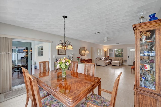 dining room with ceiling fan with notable chandelier, light tile patterned flooring, and a textured ceiling