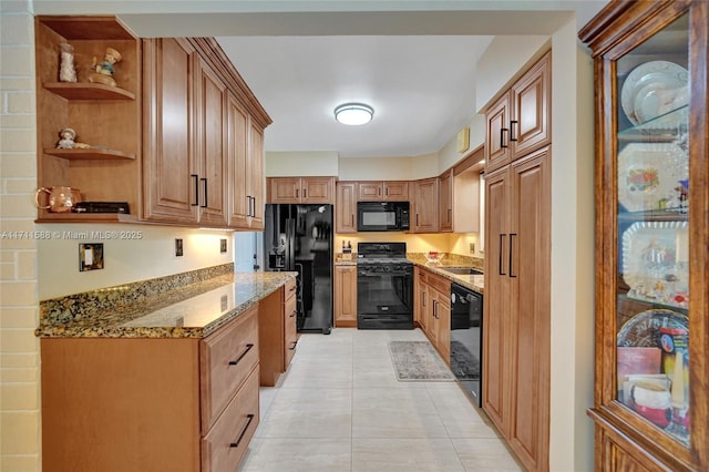 kitchen featuring light stone counters, sink, light tile patterned floors, and black appliances