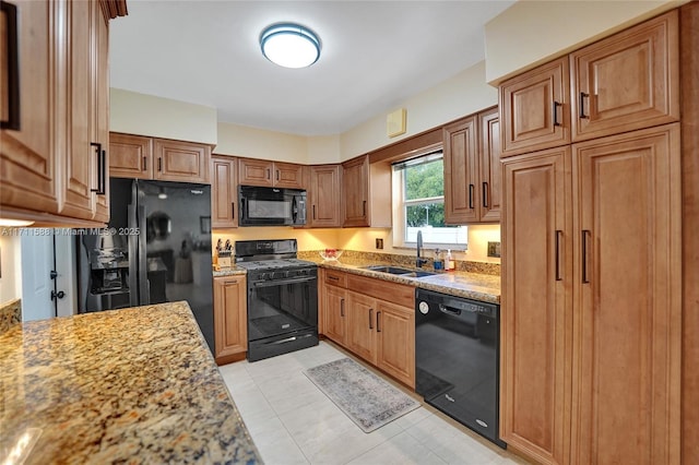 kitchen with black appliances, light stone countertops, sink, and light tile patterned floors