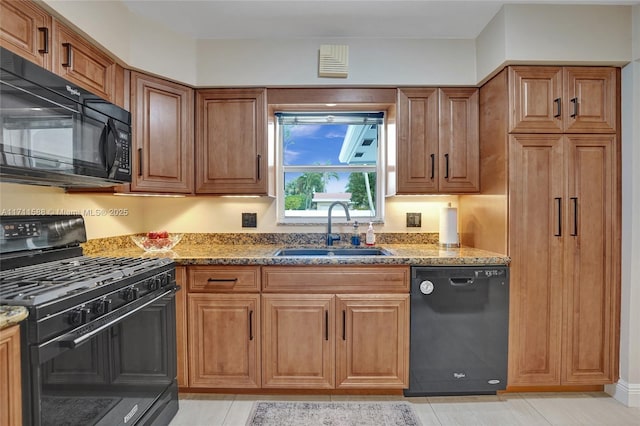 kitchen with light tile patterned floors, sink, dark stone counters, and black appliances