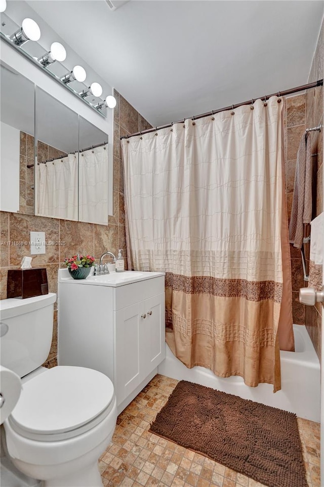 full bathroom with shower / bath combo, toilet, tile walls, and vanity