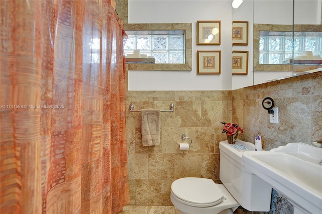 bathroom featuring toilet, sink, and tile walls