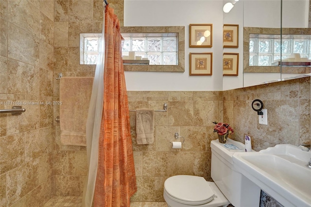 bathroom featuring a shower with shower curtain, toilet, tile walls, and sink