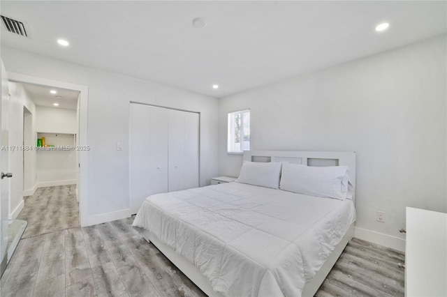 bedroom with light hardwood / wood-style floors and a closet