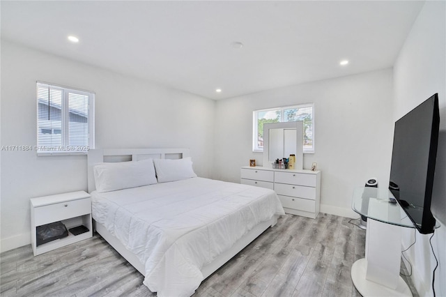 bedroom featuring multiple windows and light hardwood / wood-style flooring