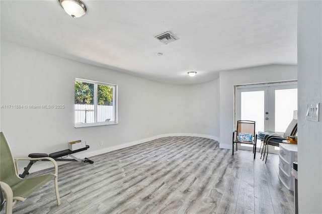 living area with french doors and light hardwood / wood-style flooring