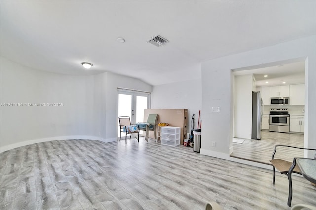 sitting room featuring light hardwood / wood-style flooring, french doors, and vaulted ceiling