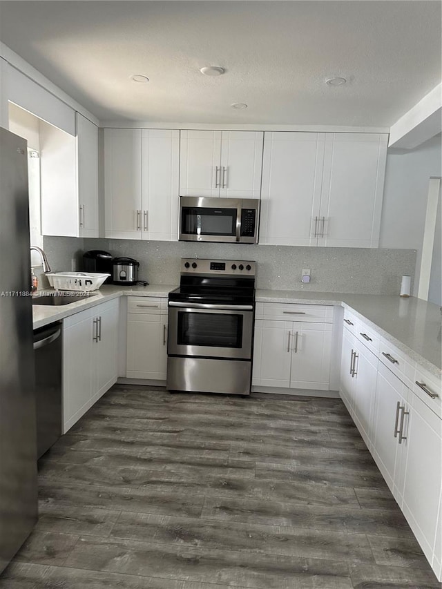 kitchen with dark hardwood / wood-style floors, white cabinetry, sink, and appliances with stainless steel finishes