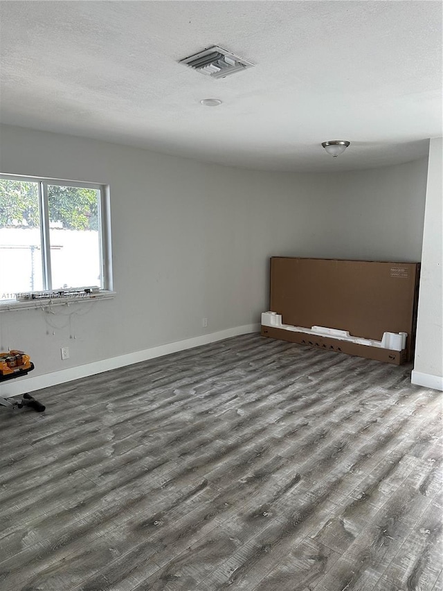 unfurnished room with dark wood-type flooring and a textured ceiling